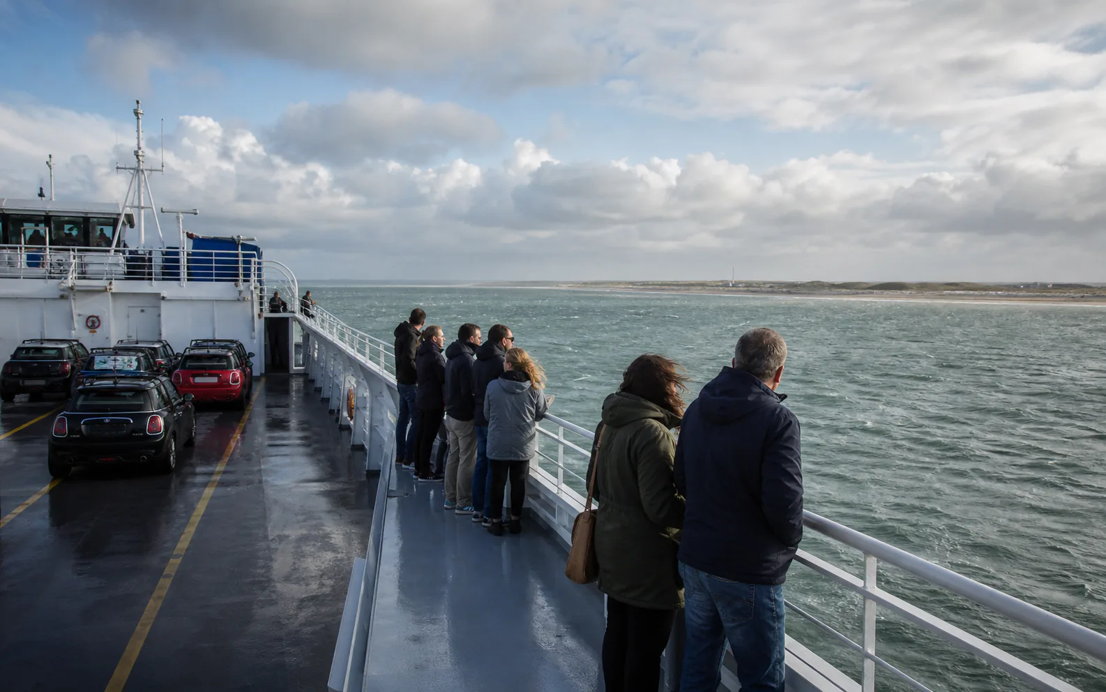 Deelnemers kijken vanaf de ferry over de Waddenzee richting Texel
